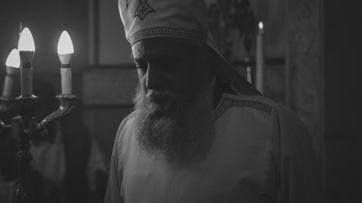 Black and white photo of an Orthodox priest during a candlelit religious ceremony in Cairo, Egypt.
